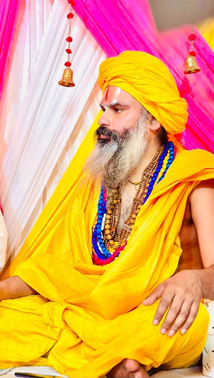 Maharaj Ji in discourse, flanked by Radha-Krishna darshan